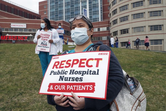 Nurses stand on a grassy hill outside the emergency entrance to Jacobi Medical Center in the Bronx borough of New York, Saturday, March 28, 2020, as they demonstrate with members of the New York Nursi ...