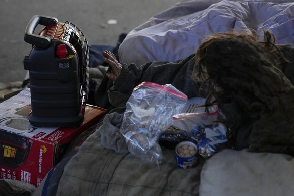 An unhoused individual warms her hand on a propane heater provided by the Orange Tent Project nonprofit during dangerously cold temperatures Friday, Jan. 23, 2026, in Chicago. (AP Photo/Erin Hooley)