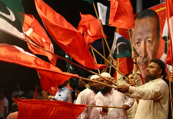 epa10662512 Supporters of Islamic political party Jamaat-e-Islami hold Turkish flags as they celebrate the victory of Turkish President Recep Tayyip Erdogan in presidential runoff, in Karachi Pakistan ...