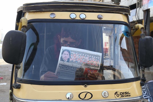 epa09881928 A Pakistani resident reads a newspaper along the roadside after Prime Minister Imran Khan, lost the vote of no-confidence in the parliament, in Karachi, Pakistan, 10 April 2022. The opposi ...