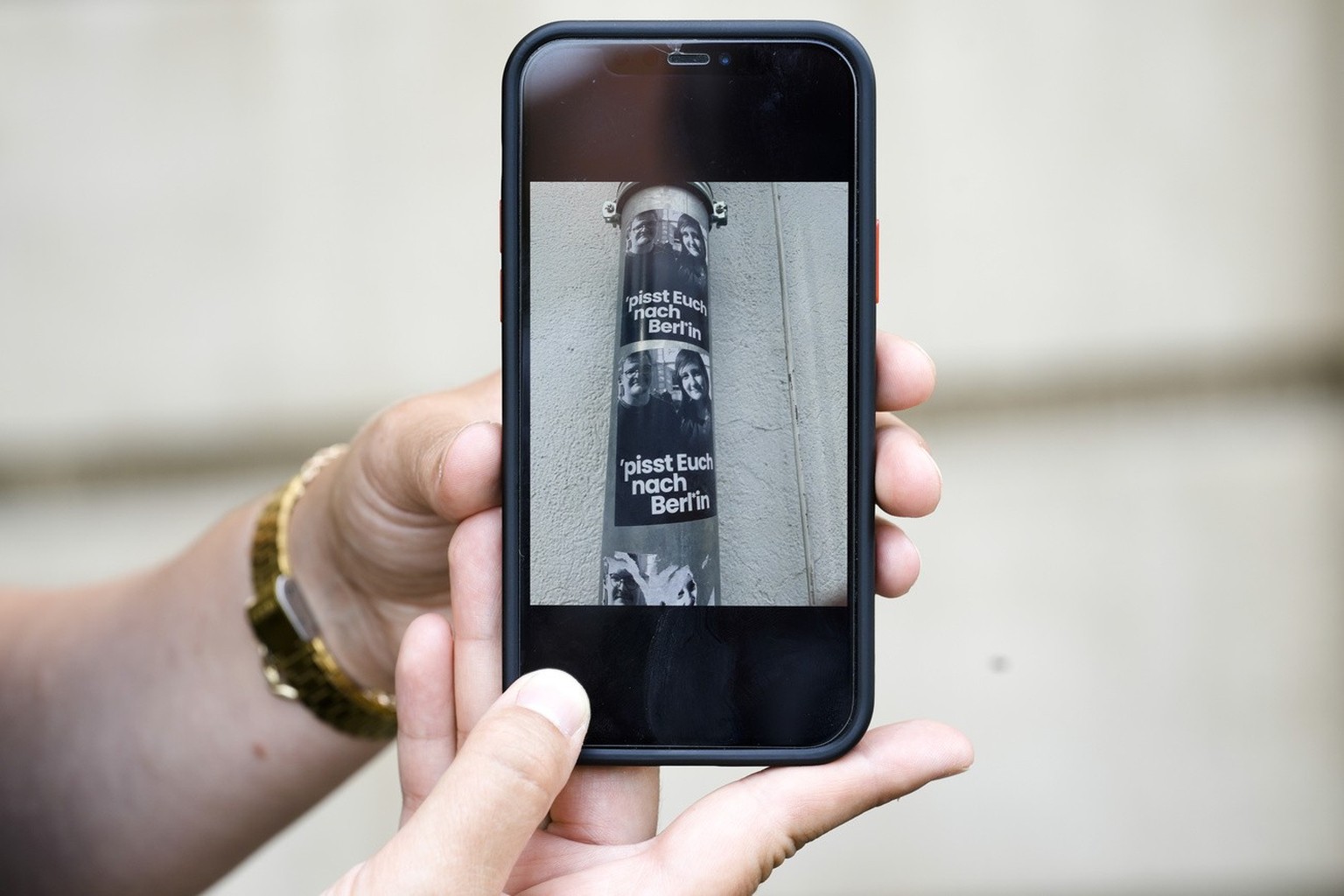 Teacher Laura Nickel shows her cell phone with pictures of stickers on a lamp pole showing images of her and colleague Max Teske with the caption &quot;piss off to Berlin&quot; during an interview wit ...