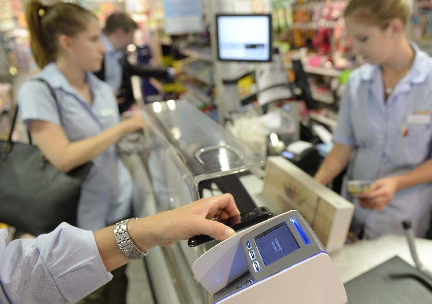 Eine Frau bezahlt mit dem Smartphone an der Kasse einer Coop Filiale in Zuerich am Dienstag, 1. Juli 2014. Mit &quot;Tapit&quot; kommt erstmals eine Smartphone App auf den Schweizer Markt, die das Bez ...