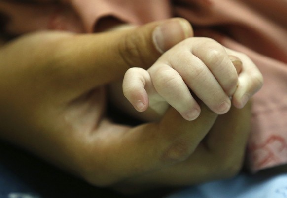 epa04340341 A Thai surrogate mother, Pattharamon Janbua (L), 21, holds the hand of her seven-month-old Down&#039;s Syndrome baby, Gammy or Naruebet Mincharoen at a hospital in Chonburi province, Thail ...