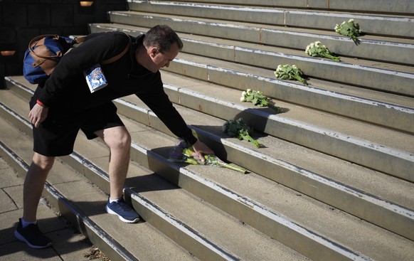 epa10568477 A man places a bouquet of flowers in the aftermath of a mass shooting which left at least five people and the gunman dead at the Old National Bank in downtown Louisville, Kentucky, USA, 11 ...