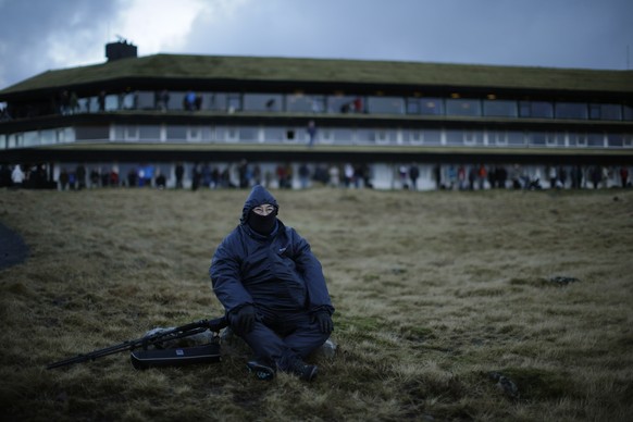 A visitor waits for the start of a total solar eclipse on a hill beside a hotel overlooking Torshavn, the capital city of the Faeroe Islands, Friday, March 20, 2015. For months, even years, accommodat ...