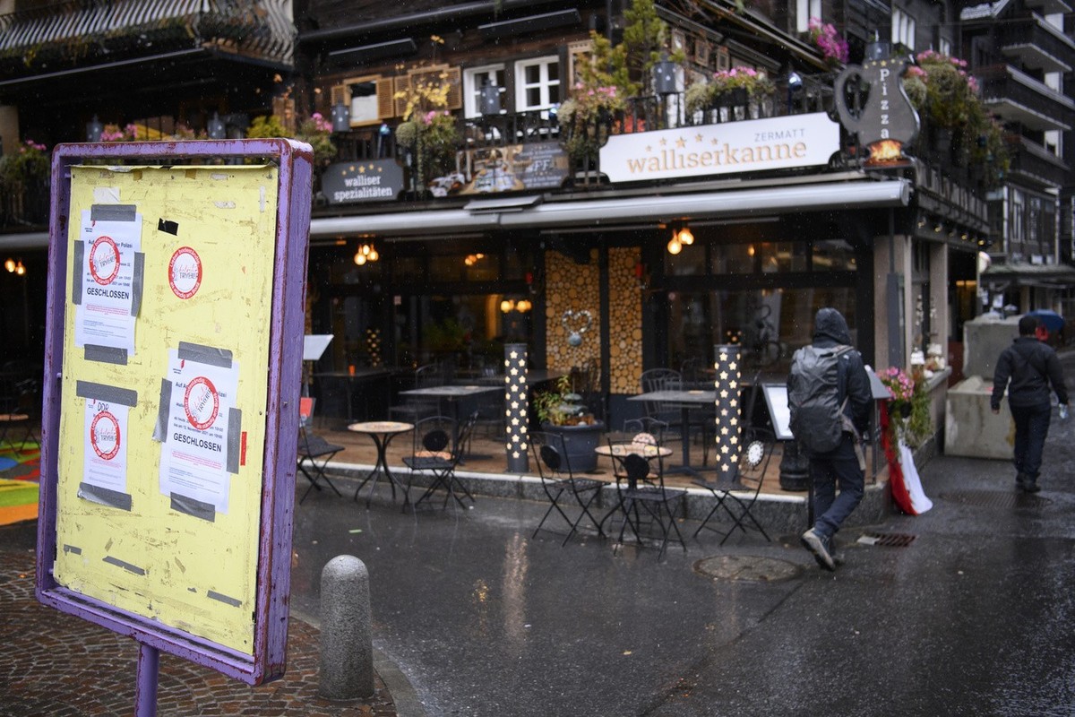 People walk past a sign that informs them that the restaurant is closed in front of the restaurant "Walliserkanne" after the restaurant was closed and the owners were arrested by the police  ...