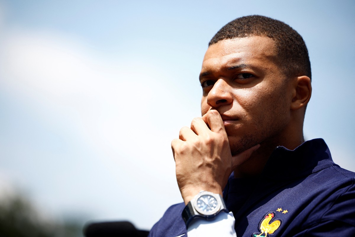 epa11387196 French soccer player Kylian Mbappe listens to French President Emmanuel Macron as he arrives for a lunch at their training camp ahead of the UEFA Euro 2024, in Clairefontaine-en-Yvelines,  ...