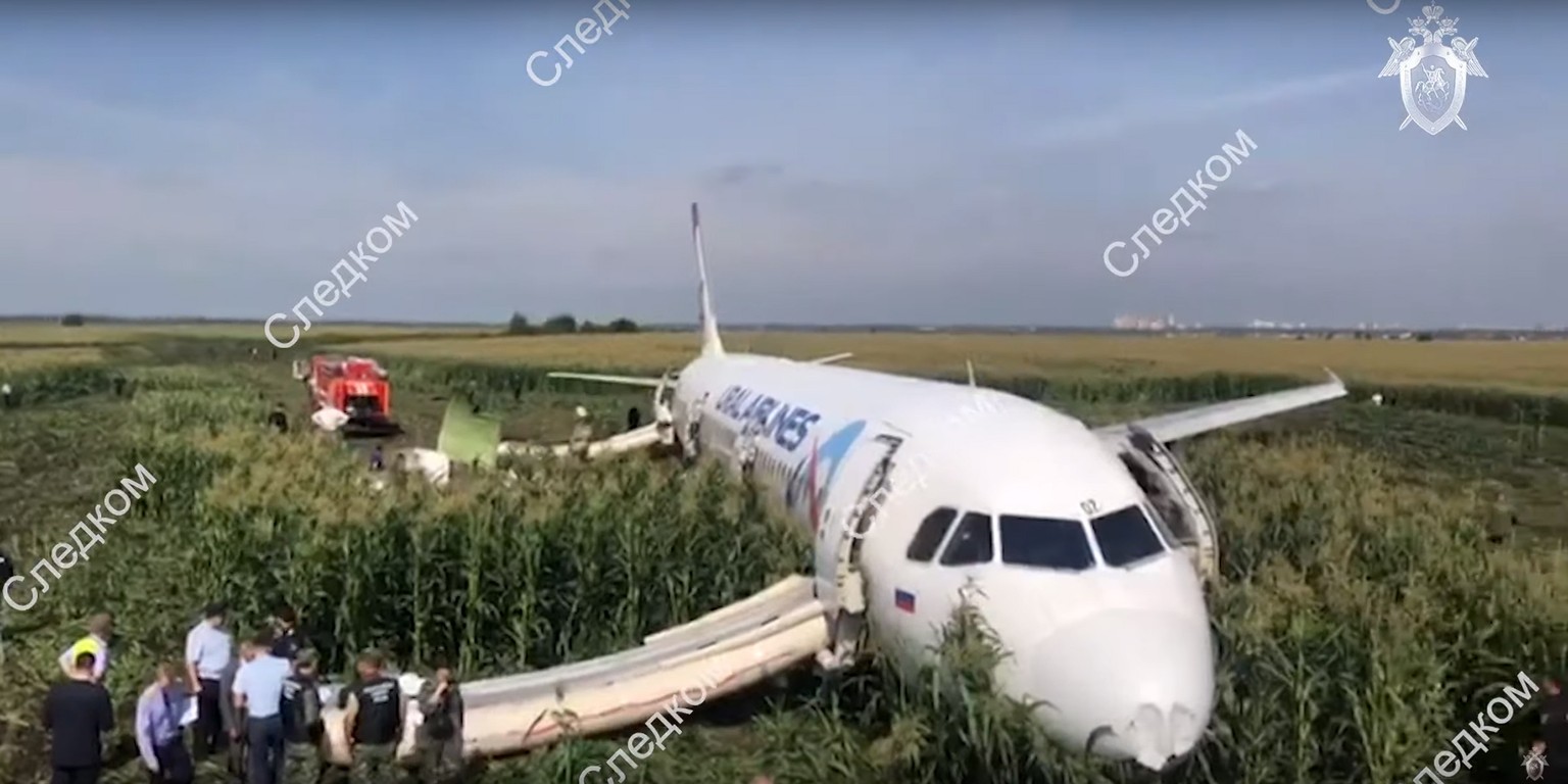 epa07774759 A handout still image taken from a video footage released by the Russian Investigative Committee shows investigators near the Ural Airlines A-321 passenger plane on the site of its emergen ...