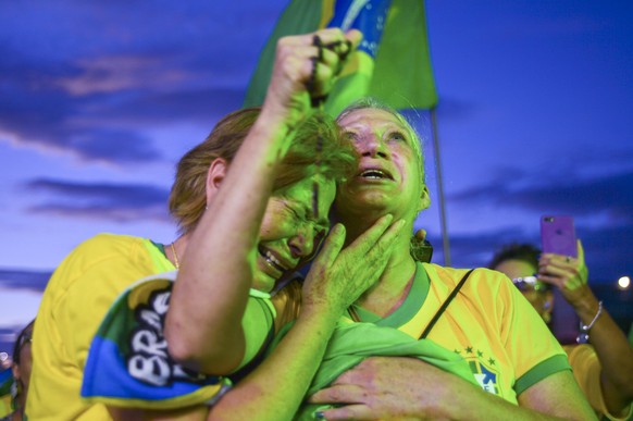 Supporters of Brazilian President Jair Bolsonaro embrace as they listen to partial results after polls closed in a presidential run-off election in Brasilia, Brazil, Sunday, Oct. 30, 2022. On Sunday,  ...
