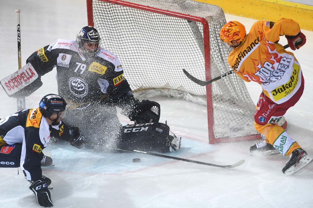 Ambri's goalkeeper Daniel Manzato, left, fights for the puck with Tiger's player Harri Pesonen, right, during the preliminary round game of National League between HC Ambri Piotta and SCL Ti ...