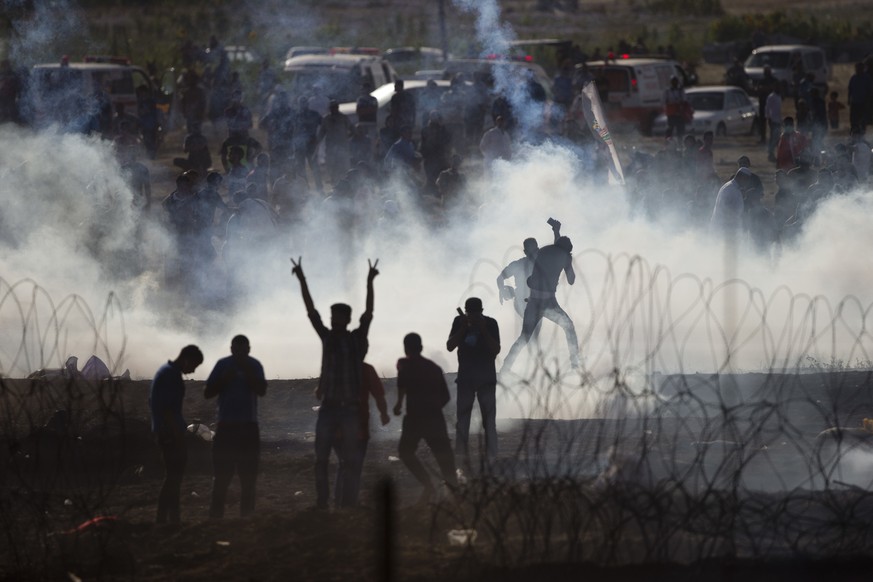 Palestinians protesters run from tear gas fired by Israeli troops in Israel Gaza border, Friday, June 8, 2018. (AP Photo/Ariel Schalit)