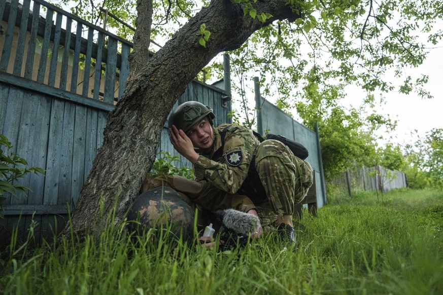 A police officer takes cover during Russian shelling in Vovchansk, Ukraine, on Saturday, May 11, 2024. (AP Photo/Evgeniy Maloletka)