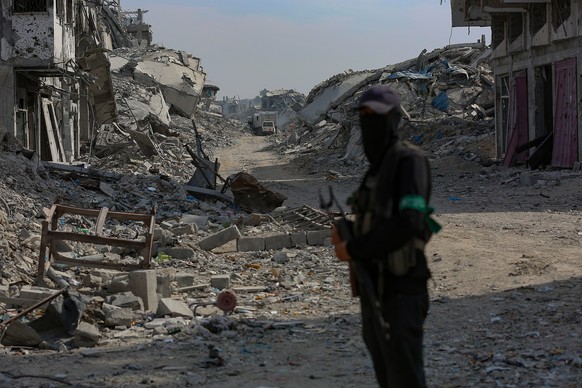 epa12499080 Fighters of the Al-Qassam Brigades, the military wing of the Hamas movement, stand guard as they search for the bodies of Israeli hostages alongside Red Cross workers in the east of the Ga ...