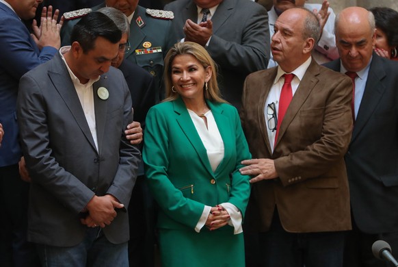 epa08151653 Interim president of Bolivia Jeanine Añez is receive by the minister of presidency, Yerko Nuñez (L), and of the government, Arturo Murillo (2R), prior to a speech in the government palace  ...