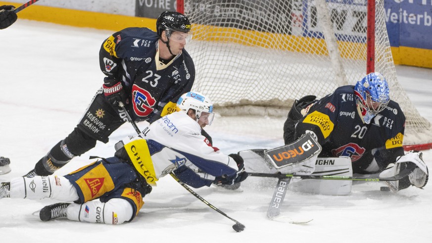 Fribourgs, Samuel Walser, links, und Goalie, Reto Berra im Duell mit Zugs, Erik Thorell, Mitte, waehrend dem Meisterschaftsspiel der National League, zwischen dem HC Fribourg-Gotteron und dem EV Zug,  ...