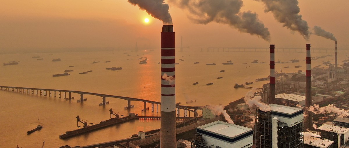The sun sets near a coal-fired power plant on the Yangtze River in Nantong in eastern China's Jiangsu province on Dec. 12, 2018. Chinese power companies bid for credits to emit carbon dioxide and ...