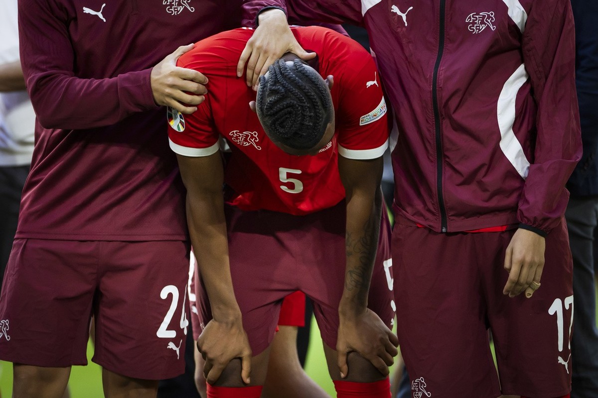 Switzerland's Manuel Akanji, center, reacts between his teammates Ardon Jashari, left, and Ruben Vargas after losing the penalty shoot-out of the quarter final match between England and Switzerla ...
