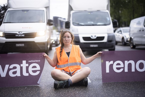 Environmental activists of Renovate Switzerland sit down on the road during a roadblock action on the motorway A1 exit in Zuerich, Switzerland on June 19, 2023. (KEYSTONE/Michael Buholzer)