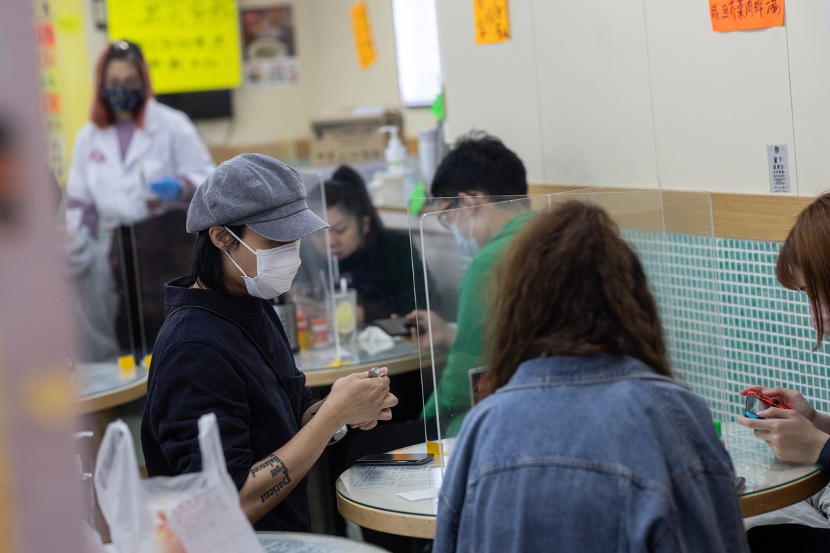 epa08347551 Patrons eat in a restaurant where tables are divided by newly installed plastic screens in Hong Kong, China, 07 April 2020. Social-distancing measures put in place by the government are li ...