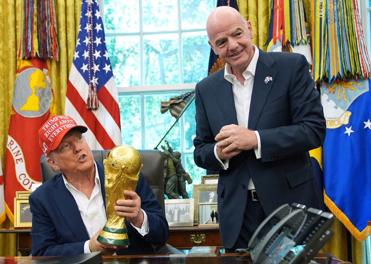 FILE - President Donald Trump holds the FIFA World Cup Winners Trophy as FIFA President Gianni Infantino looks on during an announcement in the Oval Office of the White House, Aug. 22, 2025, in Washin ...