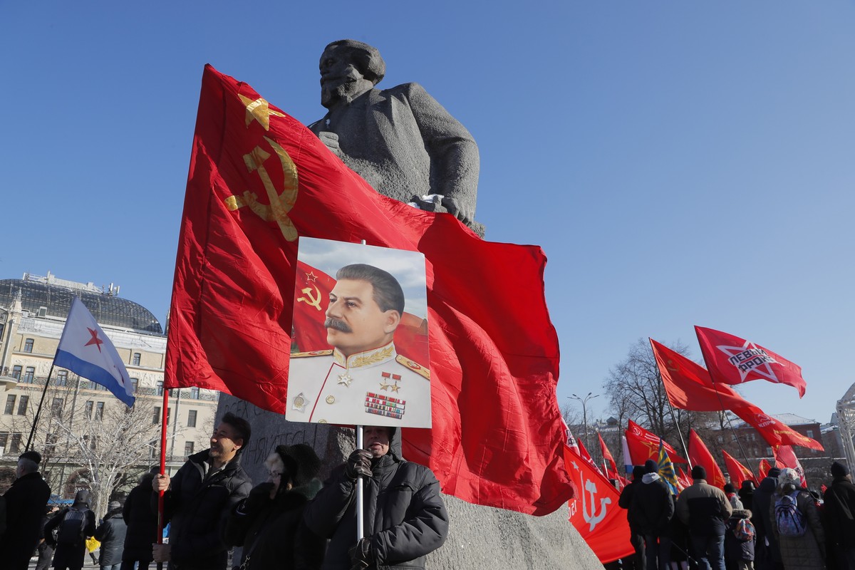 epa10485757 A Russian Communist party supporter holds a portrait of Soviet leader Joseph Stalin in front of the Karl Marx monument during a rally before a wreath-laying ceremony at the Eternal Flame a ...