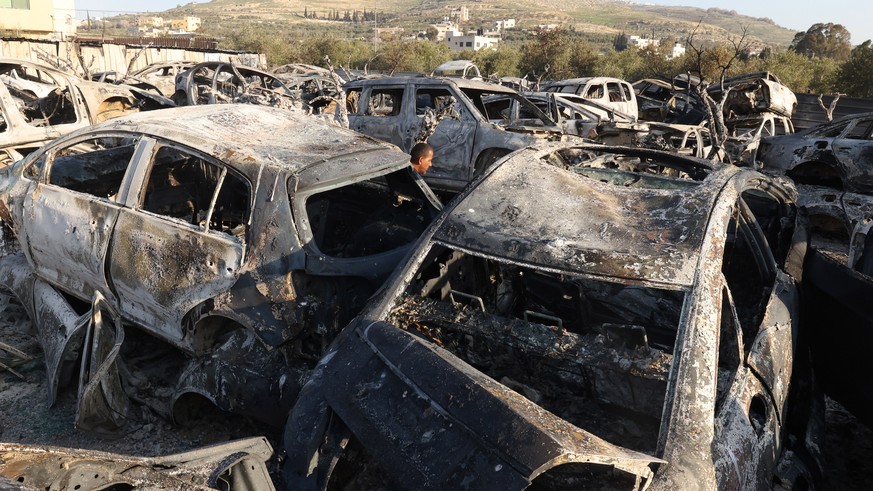 epa10493426 A damaged bulding and burned cars after a shooting attack the day before in which two Israelis were killed, near the West Bank city of Nablus, 27 February 2023. One Palestinian was killed  ...