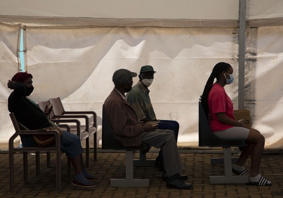 People wait to receive a dose of a COVID-19 vaccine at a centre, in Soweto, Monday, Nov. 29, 2021. The World Health Organization has urged countries not to impose flight bans on southern African natio ...