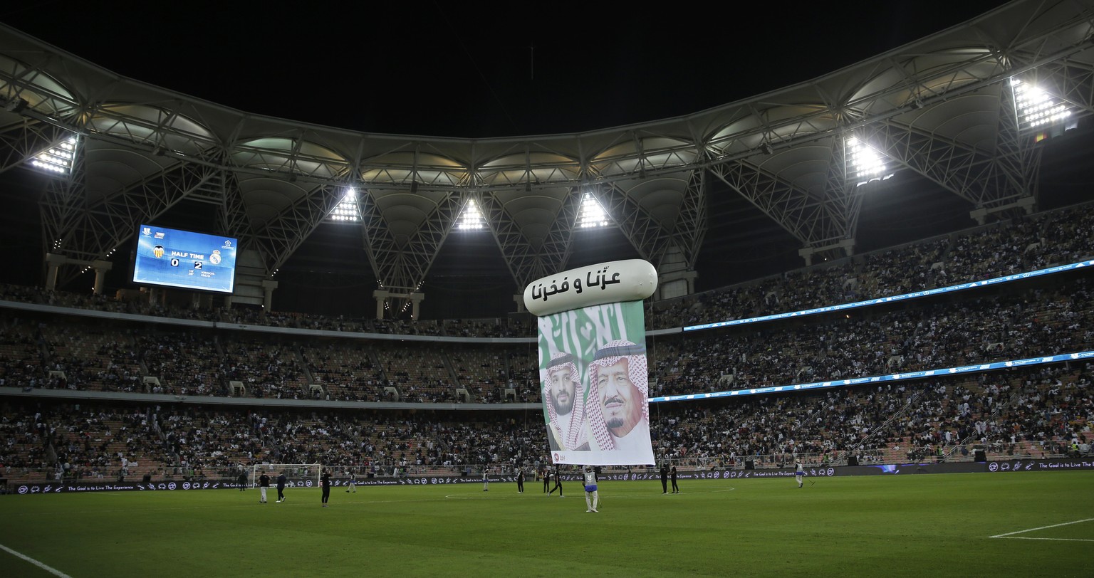 A banner is displayed on the pitch with pictures of Saudi King Salman, right, and Crown Prince Mohammed bin Salman, during halftime of the Spanish Super Cup semifinal soccer match between Real Madrid  ...