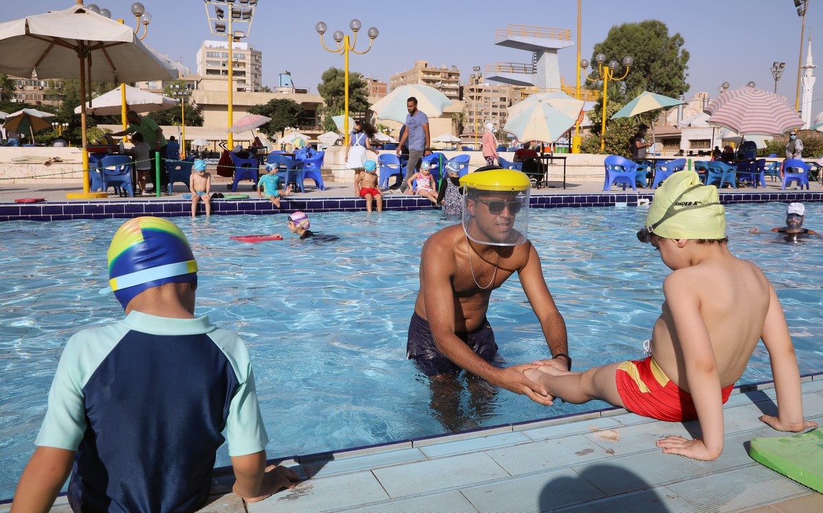 epa08540620 Coaches wear face sheilds during swimming classes at a sporting club in Cairo, Egypt, 11 July 2020. EPA/KHALED ELFIQI