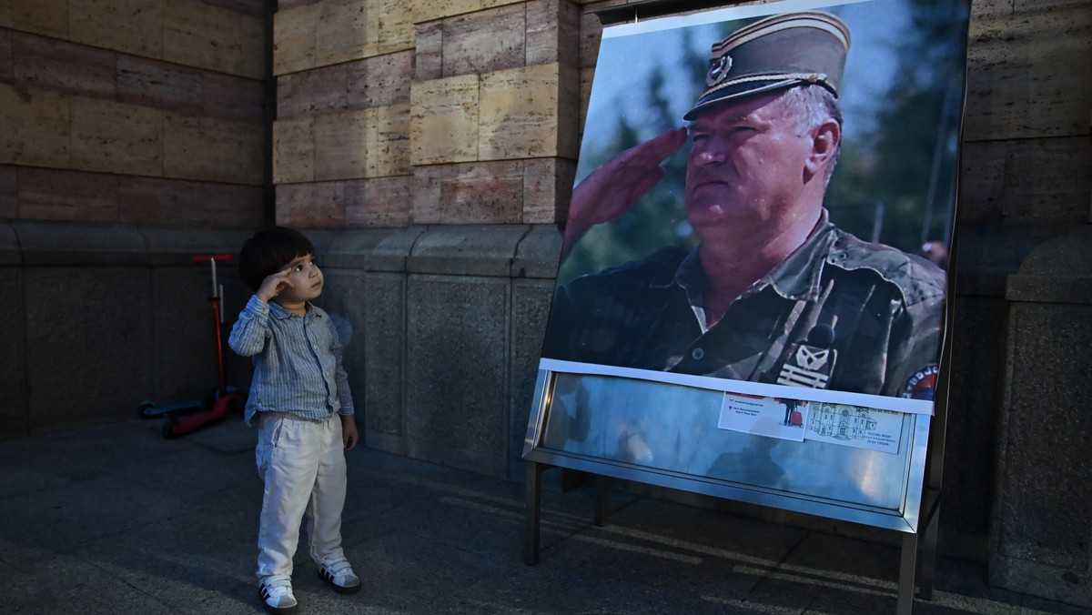 KEYPIX - A boy salutes in front of poster of former Bosnian Serb wartime general Ratko Mladic, outside a church in Banja Luka, Bosnia-Herzegovina, Thursday, Aug. 27, 2026. (AP Photo/Radivoje Pavicic)