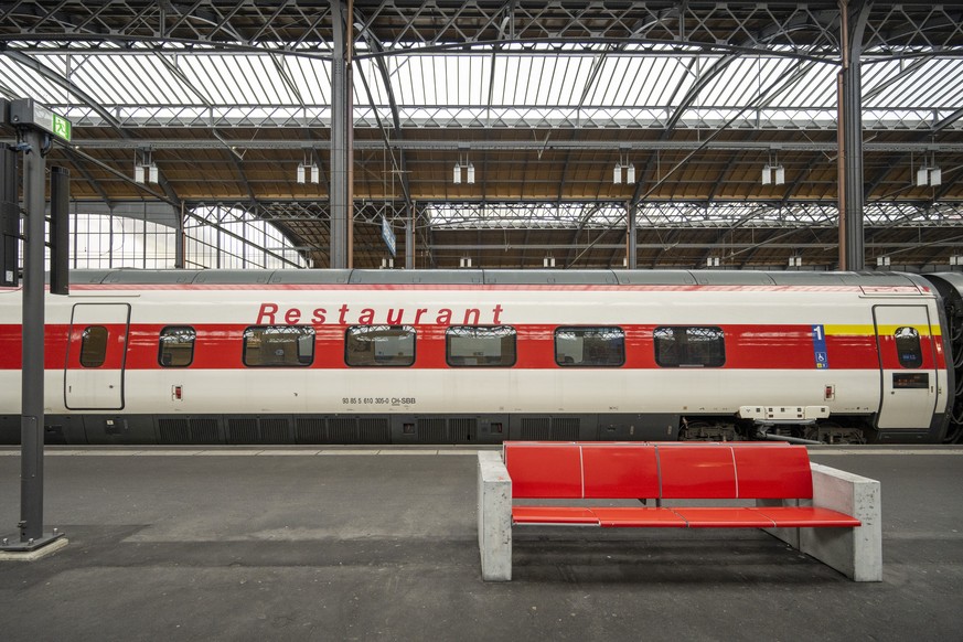 Ein roter Sitzbank steht auf einem Perron vor einem Restaurant-Wagen der SBB im Bahnhof in Basel, am 5. Dezember 2023. (KEYSTONE/Georgios Kefalas)