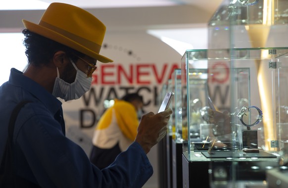 A visitor takes photos with his smartphone of a watch from Louis Moinet displayed at Geneva Watch Days Official pavilion, during the 2020 Geneva Watch Days, in Geneva, Switzerland, Friday, August 28,  ...