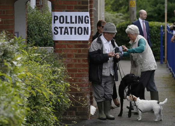 People with their dogs arrive at a polling station in Cudham, England, Thursday, May 22, 2014. Britain is going to poll for the European Parliament and local elections. (AP Photo/Sang Tan)