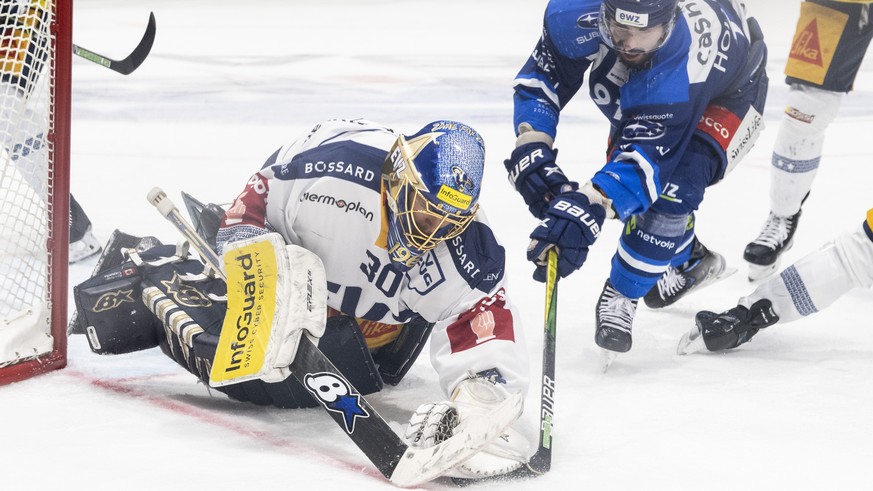 Zugs Torhueter Leonardo Genoni, links, kaempft um den Puck gegen Zuerichs Denis Hollenstein, rechts, im sechsten Eishockey Playoff-Finalspiel der National League zwischen den ZSC Lions und dem EV Zug  ...