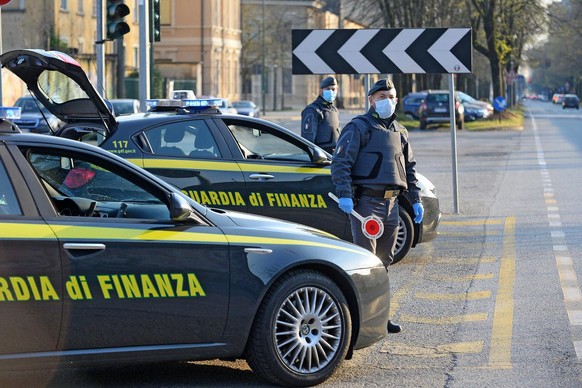 epa08338279 Italian Guardia di Finanza (Finance Police) officers wearing protective masks verify the legitimacy of the movements of some motorists, in compliance with the DCPM issued for the containme ...