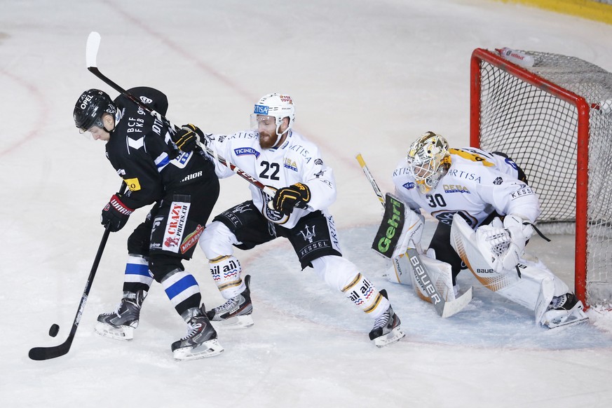 Fribourgs Killian Mottet, links, im Kampf mit Luganos Stefan Ulmer und Luganos Torhueter Elvis Merzlikins, im vierten Eishockey Playoff-Viertelfinalspiel der National League zwischen dem HC Fribourg-G ...