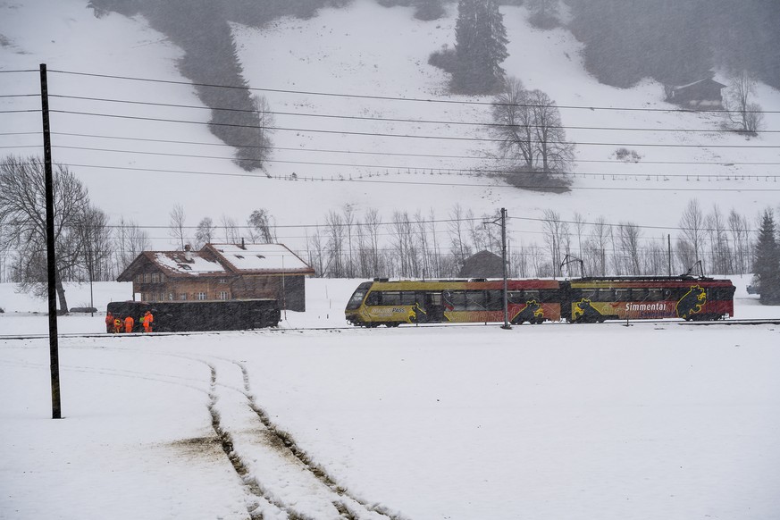 Workers walk past a derailed coache of the GoldenPass train of the Company Montreux-Oberland Bernois (MOB) at the scene of a train crash in Boden near Lenk, in the Canton of Bern, Switzerland, Wednesd ...