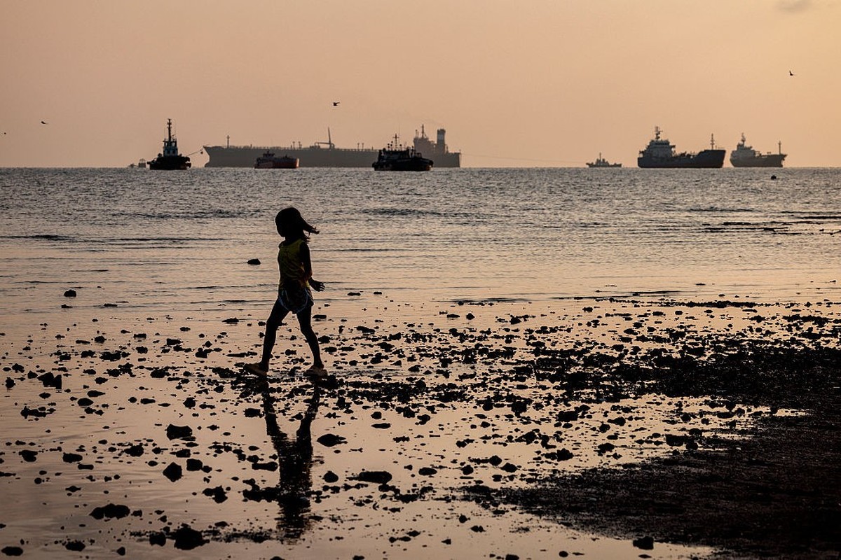 LIMAY, PHILIPPINES - APRIL 01: Children play along the shore as the Panamanian-flagged Tiger Wings (L), carrying crude oil from Russia, is seen moored off the Petron oil refinery on April 1, 2026 in L ...