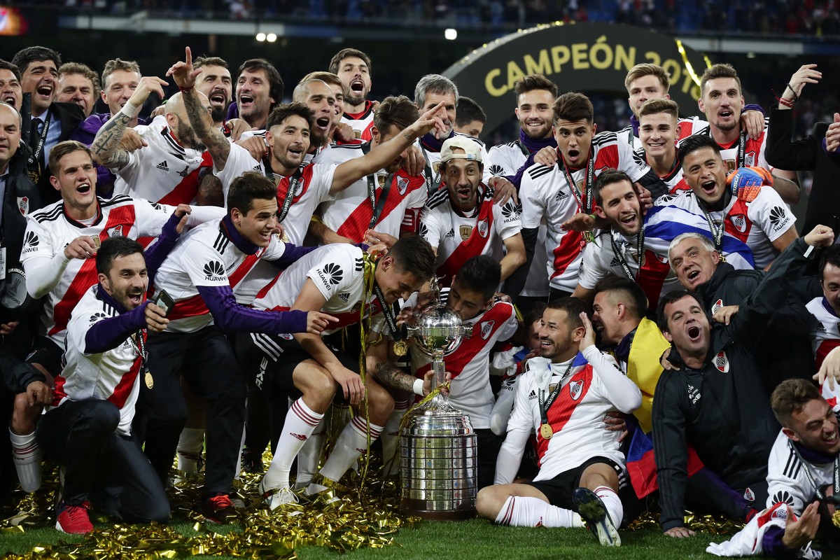 Players of Argentina's River Plate celebrate with the trophy after beating Argentina's Boca Juniors in the Copa Libertadores final soccer match at the Santiago Bernabeu stadium in Madrid, Sp ...