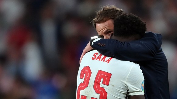 epa09338849 Headcoach Gareth Southgate (R) of England comforts Bukayo Saka after failing to score during the penalty shoot out during the UEFA EURO 2020 final between Italy and England in London, Brit ...