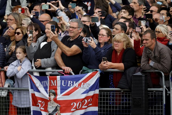 People wait along the route where the coffin of Queen Elizabeth II will be pulled on a gun carriage following her funeral service in Westminster Abbey in central London, Monday, Sept. 19, 2022. (Sarah ...