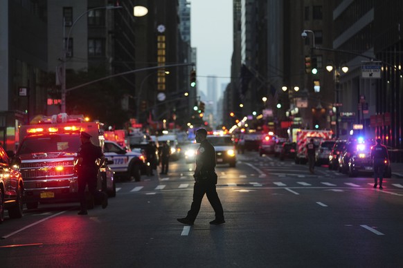 First responders gather on 52nd Street outside a Manhattan office building where two people were shot, including a New York police officer, Monday, July 28, 2025, in New York. (AP Photo/Angelina Katsa ...
