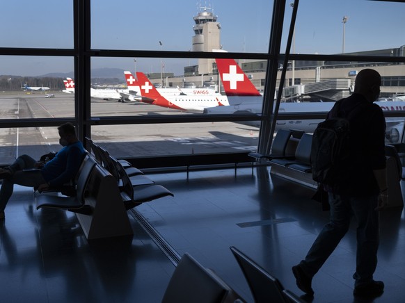 epa09091912 Passengers wearing face masks wait before boarding in an airplane in front of parked Swiss International Air Lines airplanes at the Zuerich Airport (Flughafen Zuerich) amid the coronavirus ...