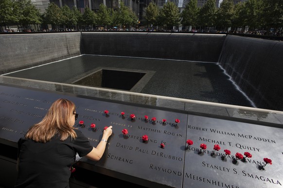 Norma Molina, of San Antonio, Texas, leaves flowers by the names of firefighters from Engine 33 at the September 11 Memorial, Monday, Sept. 9, 2019, in New York. Her boyfriend Robert Edward Evans, a m ...