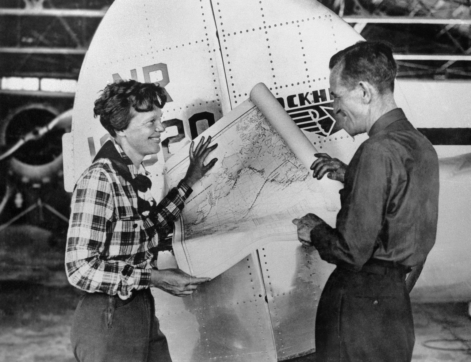 In this undated photo, aviator Amelia Earhart, left, and navigator Fred Noonan pose with a map of the Pacific Ocean showing the planned route of their round-the-world flight. (AP Photo)