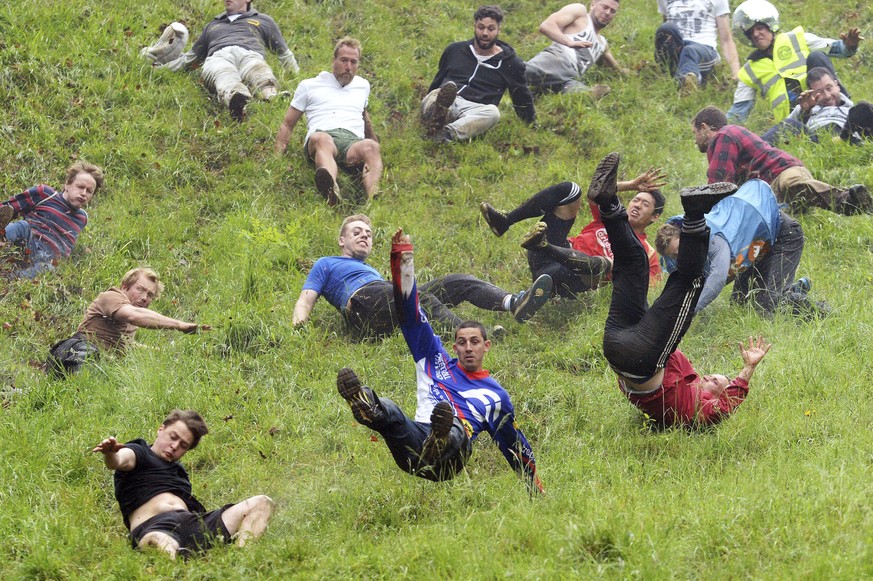 Chris Anderson, centre, on his way to winning the first race of the annual unofficial cheese rolling at Cooper's Hill in Brockworth, England, Monday May 29, 2017, where a cheese has been chased down t ...