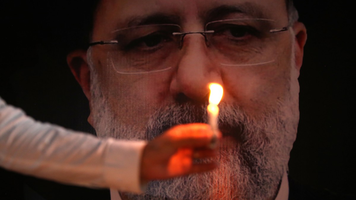 epa11364241 A Shiite Muslim holds a candle in front of photo of Iran's late president Ebrahim Raisi, at the Khana-e-Farhang Iranian culture centre in Peshawar, Pakistan, 23 May 2024. Iranian pres ...