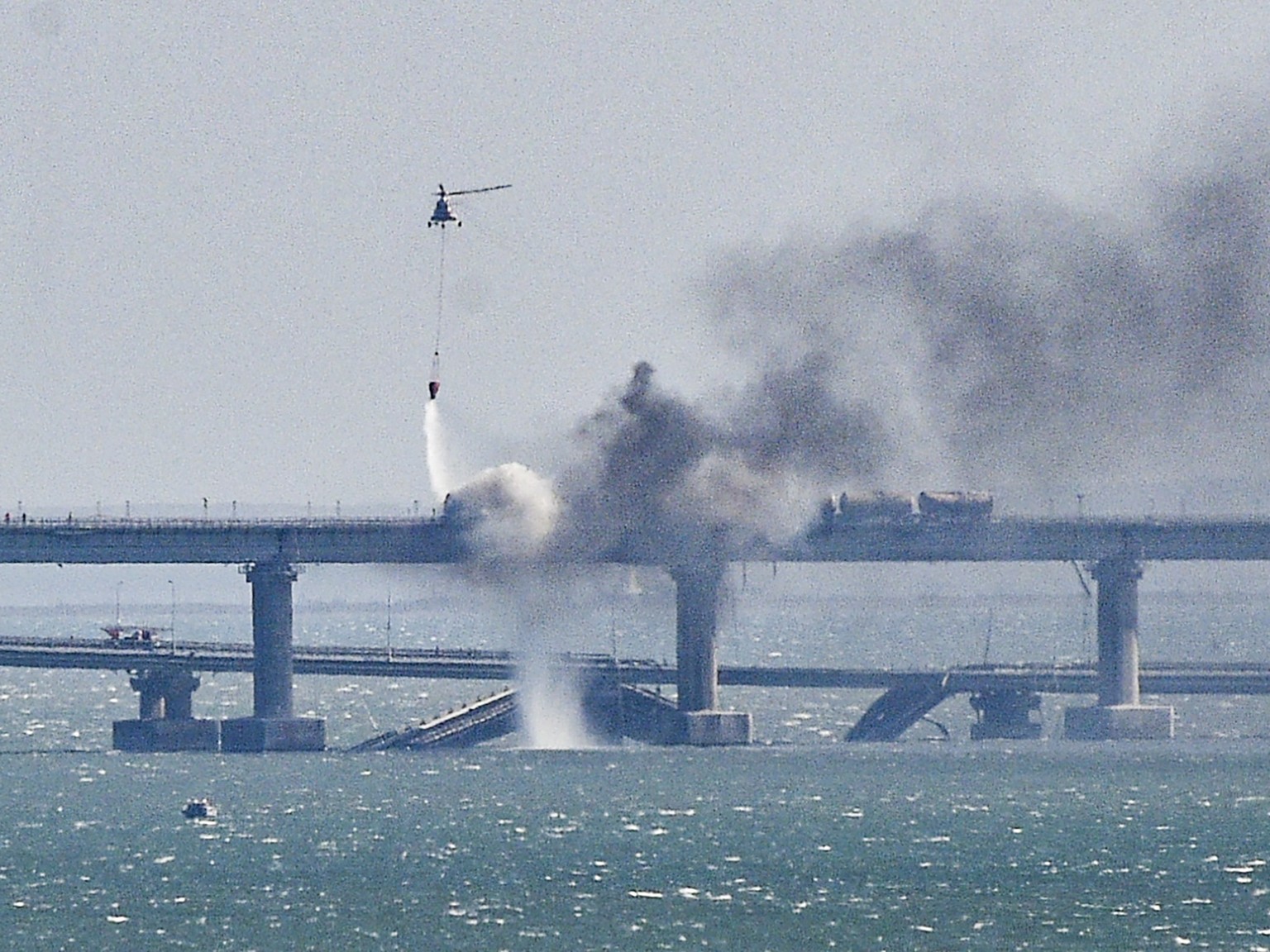 epa10731595 (FILE) - A firefighting helicopter pours water on fire on a collapsed section of bridge over the Kerch Strait in Crimea, Oct. 8, 2022. EPA/Stringer