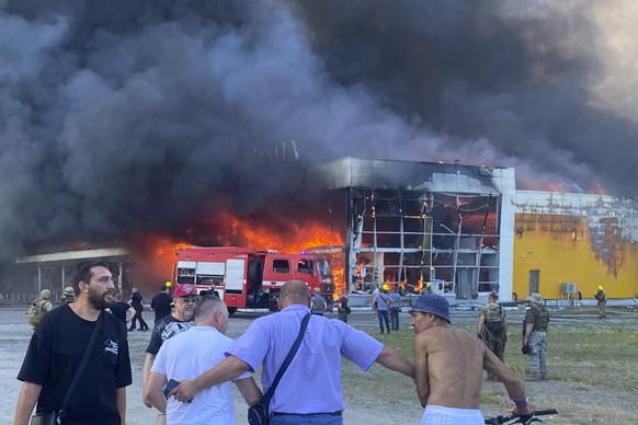 People watch as smoke bellows after a Russian missile strike hit a crowded shopping mall, in Kremenchuk, Ukraine, Monday, June 27, 2022. Ukrainian officials say scores of civilians are feared killed o ...