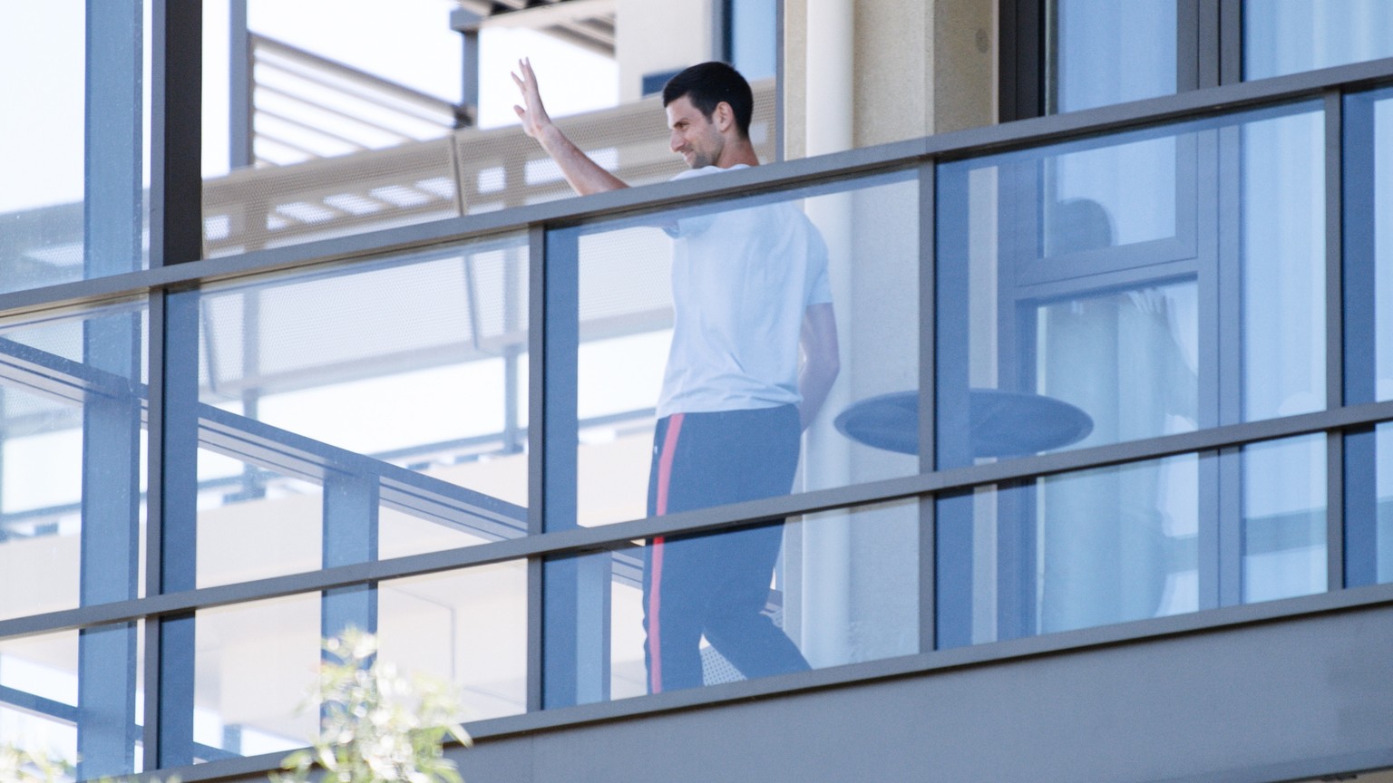 epa08947628 Novak Djokovic on the balcony of the M Suites accomodation, where some Australian Open competitors are currently under quarantine after testing positive for Covid-19, in North Adelaide, Au ...